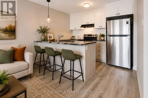A modern kitchen with a refrigerator, sink, and bar stools.