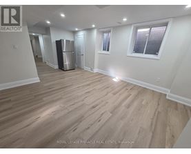 A spacious room with wooden flooring and white walls.