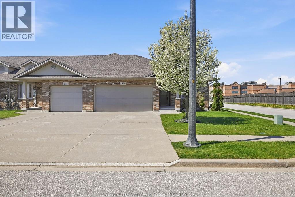 A house with a garage and a tree in front of it.