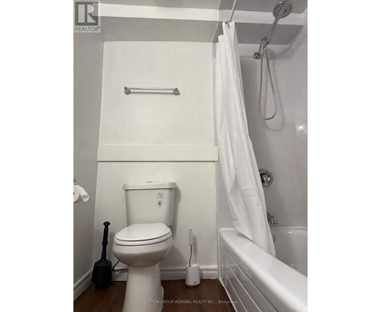 A white toilet with a white shower curtain in a bathroom.