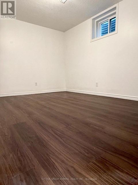 A room with wooden flooring and a window with blinds.