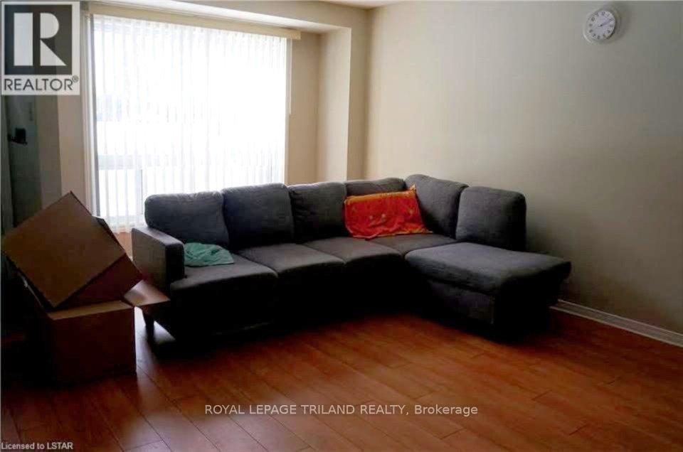 A grey couch with a red pillow is in a room with wooden floors.
