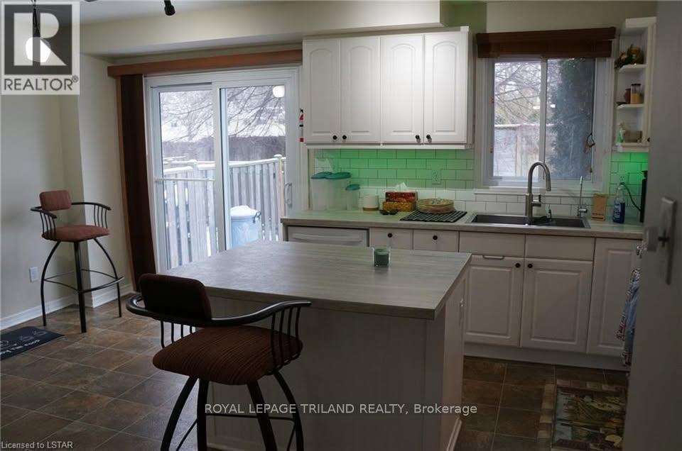 A kitchen with white cabinets and a green backsplash.