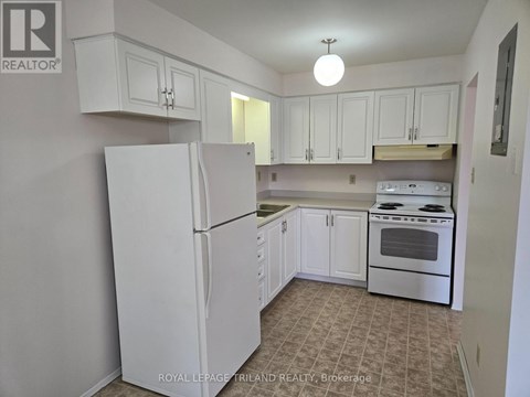 A white refrigerator stands in a kitchen with white cabinets.