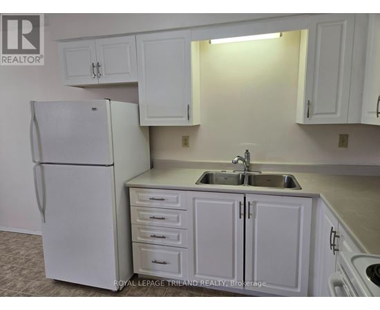A white refrigerator is in a kitchen with white cabinets.