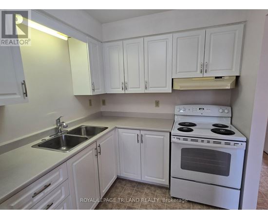 A white kitchen with a stove, sink, and cabinets.