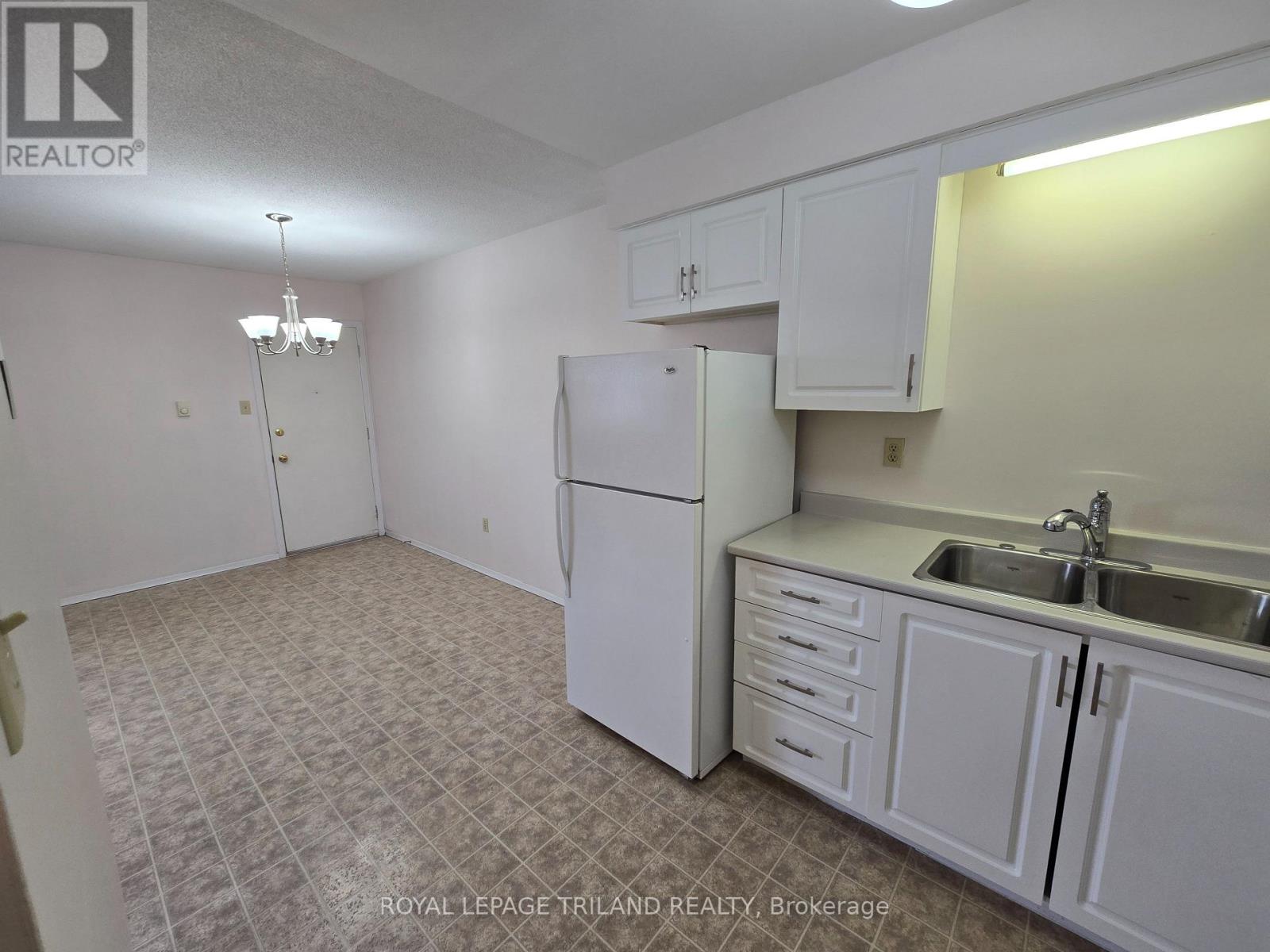 A kitchen with white cabinets and a white refrigerator.