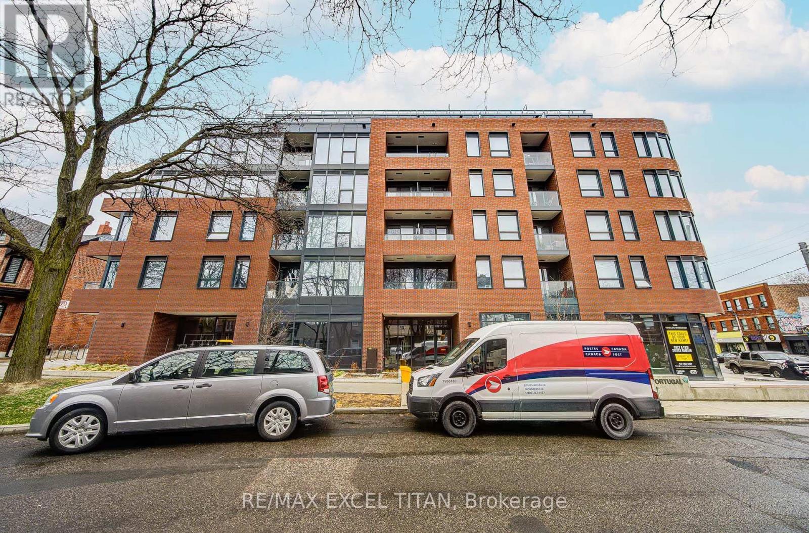 A grey van is parked in front of a tall building.