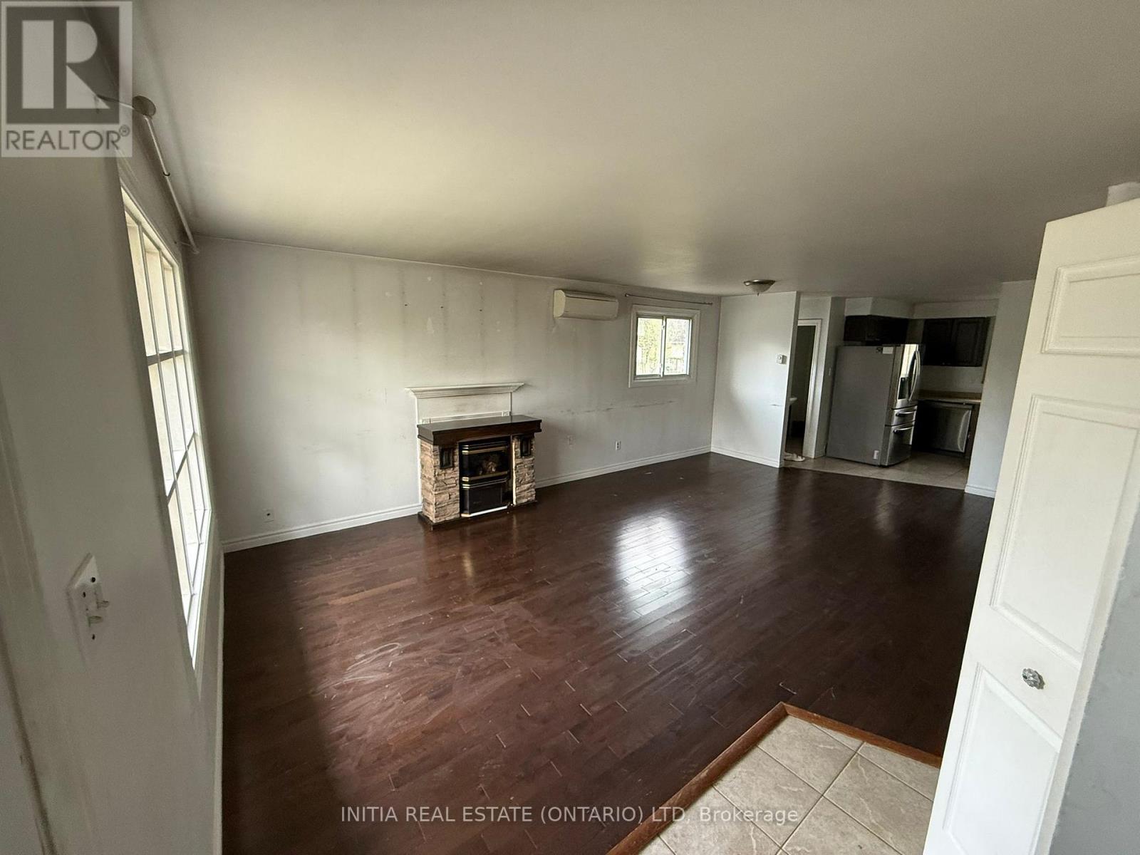 A room with wood flooring and a fireplace in the middle.