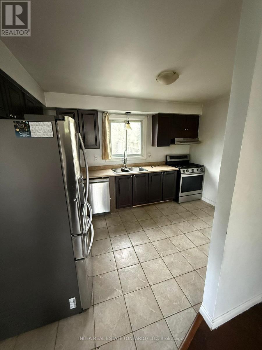 A kitchen with a refrigerator, microwave, oven, and sink.