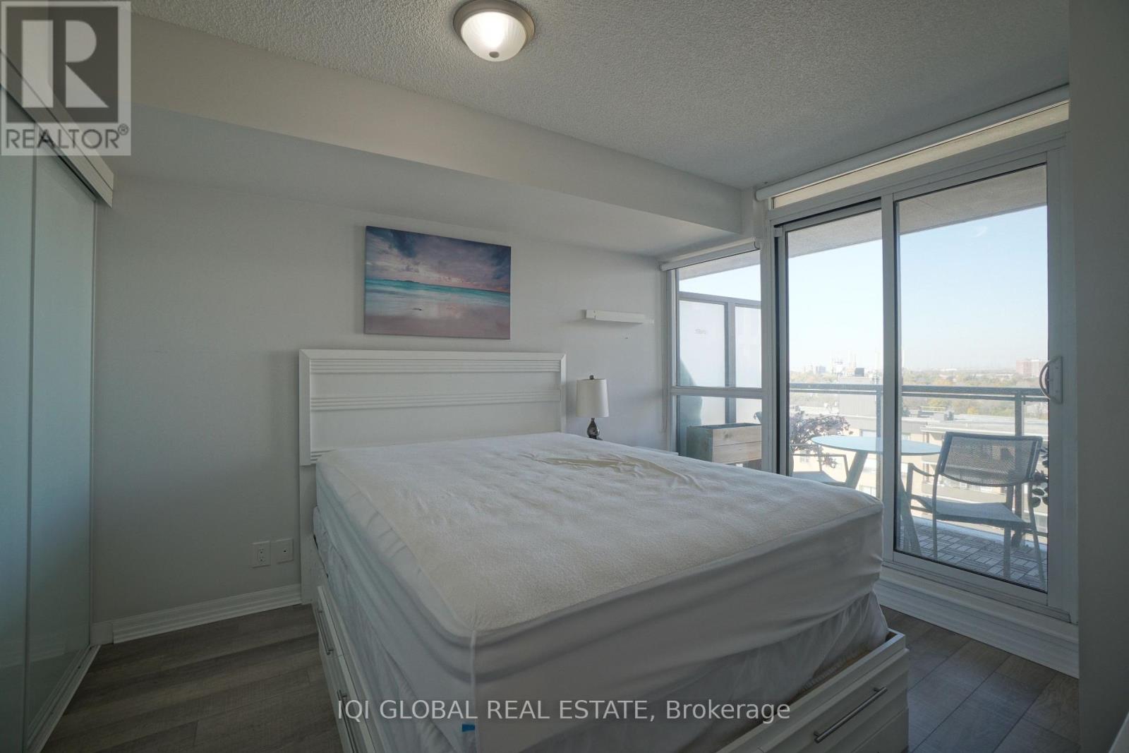 A bedroom with a large bed and a view of the outside through the window.