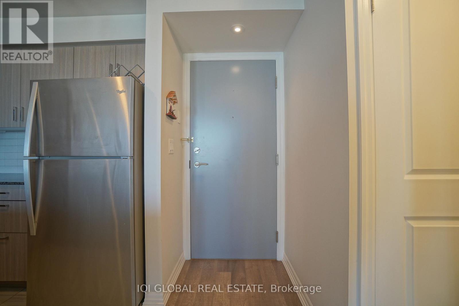 A kitchen with a stainless steel refrigerator and a door leading to another room.