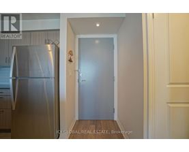A kitchen with a stainless steel refrigerator and a door leading to another room.