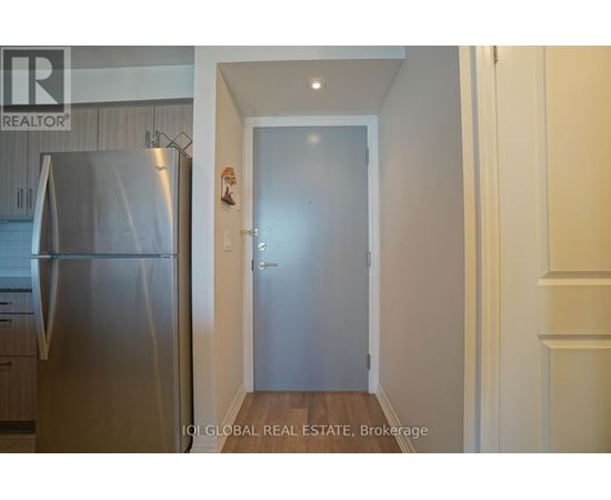 A kitchen with a stainless steel refrigerator and a door leading to another room.