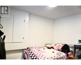 A bedroom with a bed covered in a Hello Kitty print blanket and a white wall.