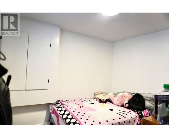 A bedroom with a bed covered in a Hello Kitty print blanket and a white wall.