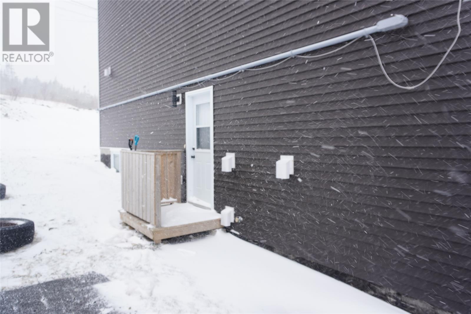 A small white door is on a black building.