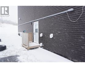 A small white door is on a black building.