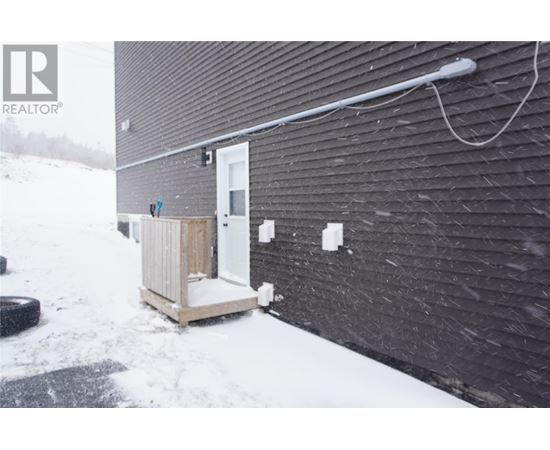 A small white door is on a black building.