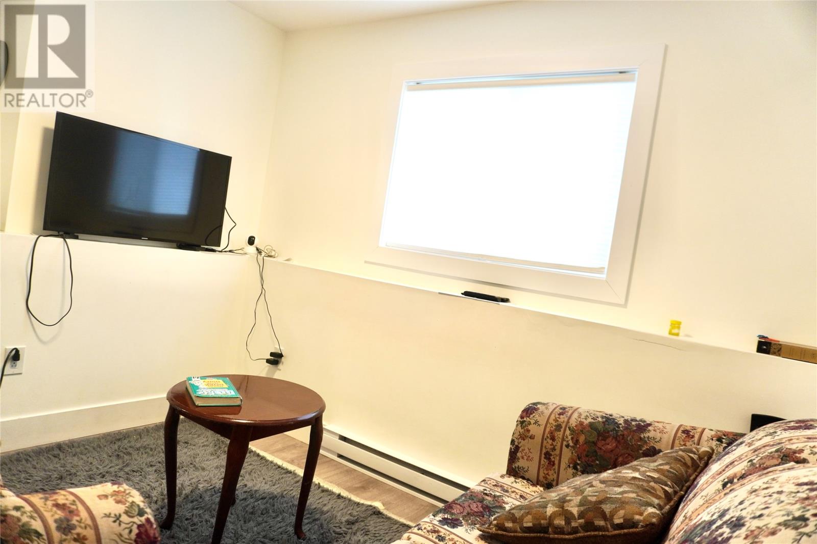 A living room with a couch, a table, and a flat screen TV mounted on the wall.