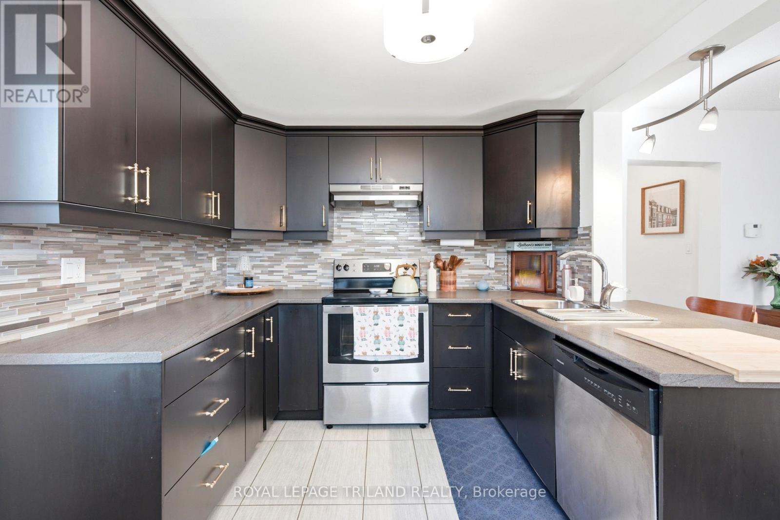 A modern kitchen with dark wood cabinets and stainless steel appliances.
