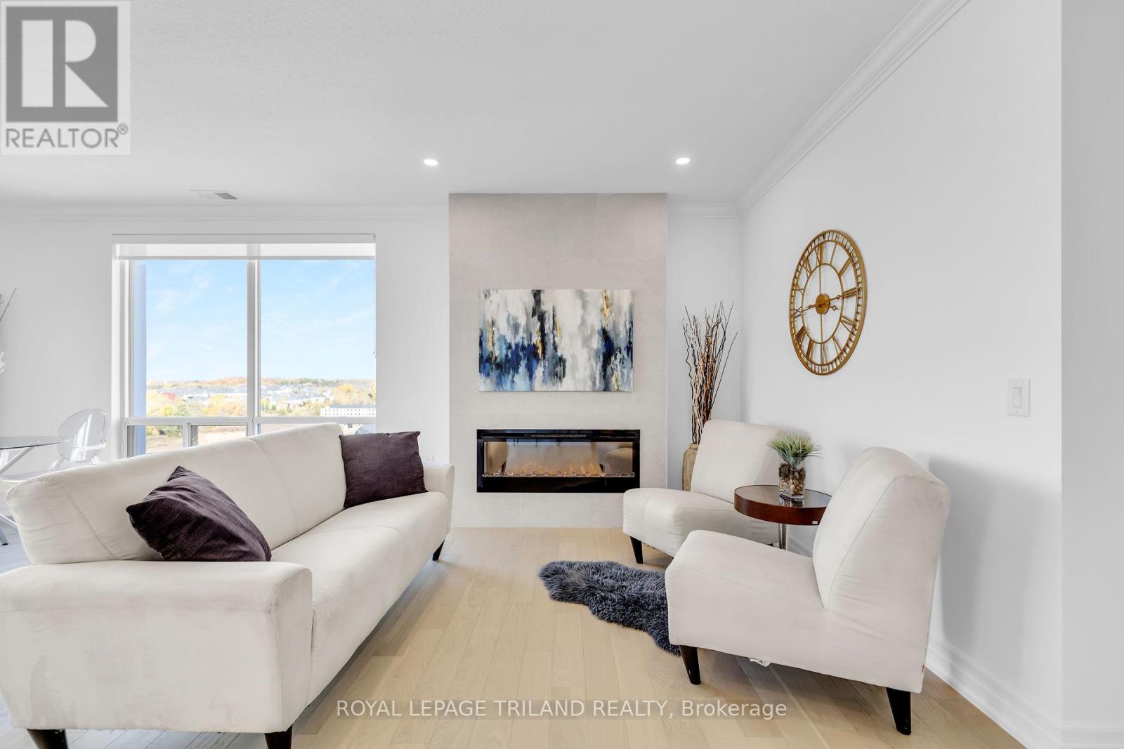 A living room with a white couch, a white chair, and a fireplace with a painting above it.