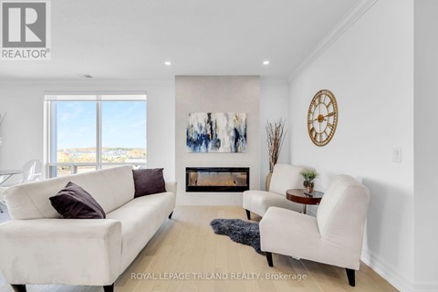 A living room with a white couch, a white chair, and a fireplace with a painting above it.