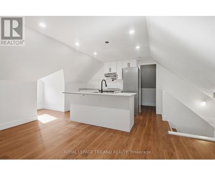A white kitchen with wooden floors and a staircase.