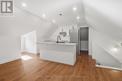 A white kitchen with wooden floors and a staircase.