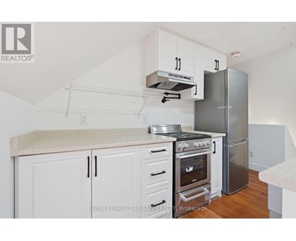A kitchen with white cabinets and a stainless steel refrigerator.