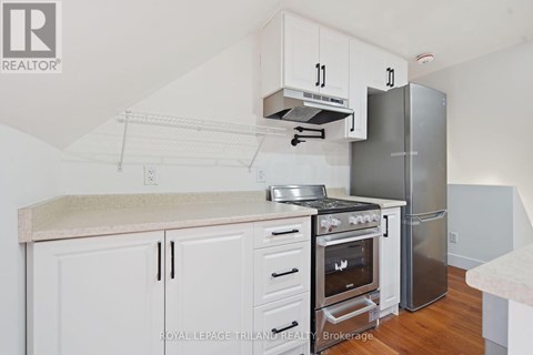 A kitchen with white cabinets and a stainless steel refrigerator.