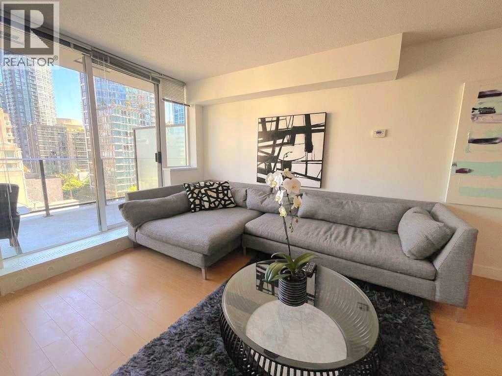 A living room with a grey sofa and a coffee table with a plant on it.