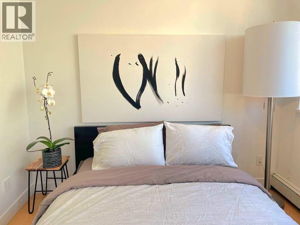 A bedroom with a large bed and a large abstract painting on the wall.