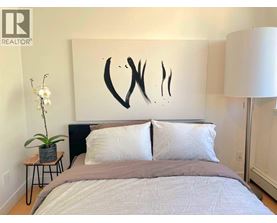 A bedroom with a large bed and a large abstract painting on the wall.