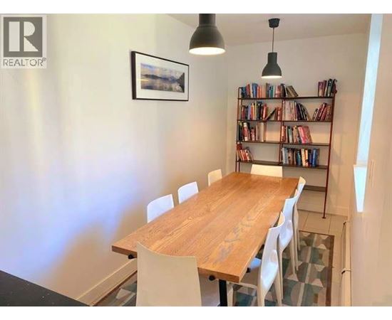 A dining room with a wooden table and chairs.