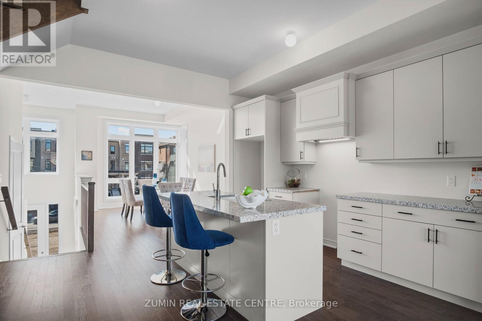 A modern kitchen with white cabinets and a blue bar stool.