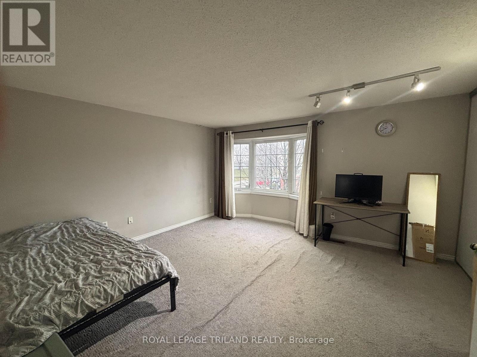 A bedroom with a bed, a television, and a window.