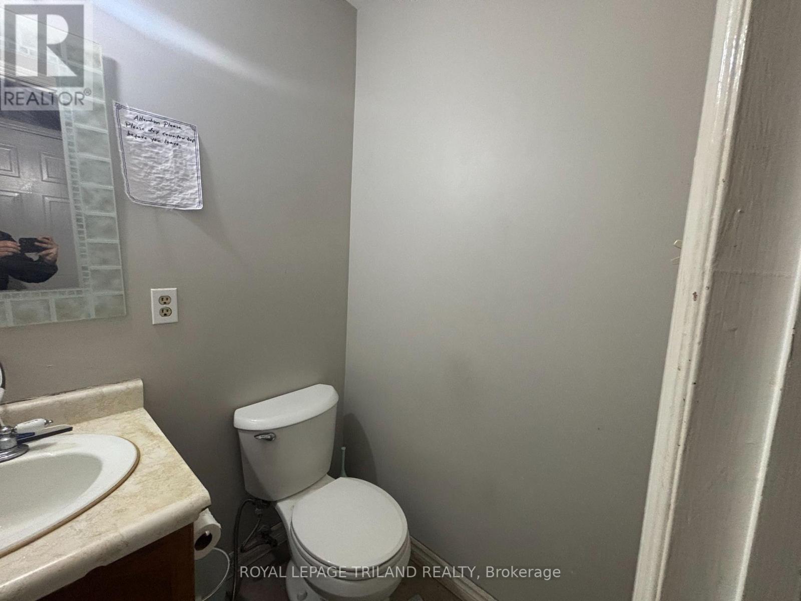 A white toilet in a small bathroom with a sink and a mirror.