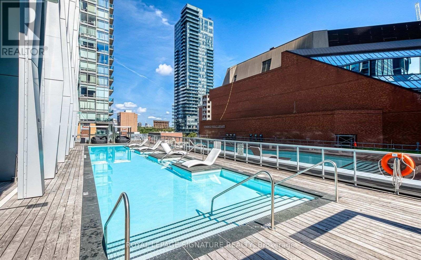 A pool area with a wooden deck and a metal railing.