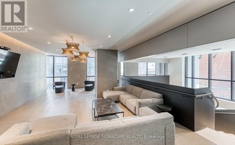 A modern living room with a large grey sofa and a glass coffee table.