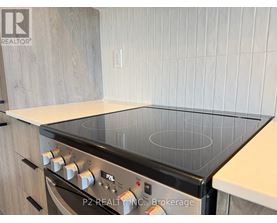 A modern kitchen with a stove top oven and wooden cabinets.