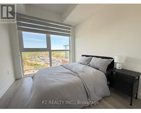 A bedroom with a large bed and a view of a cityscape through the window.