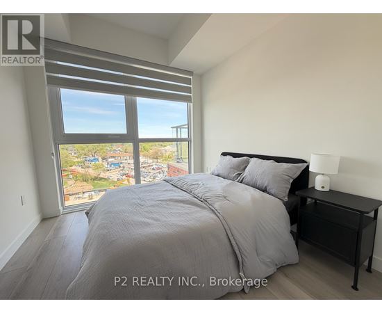 A bedroom with a large bed and a view of a cityscape through the window.