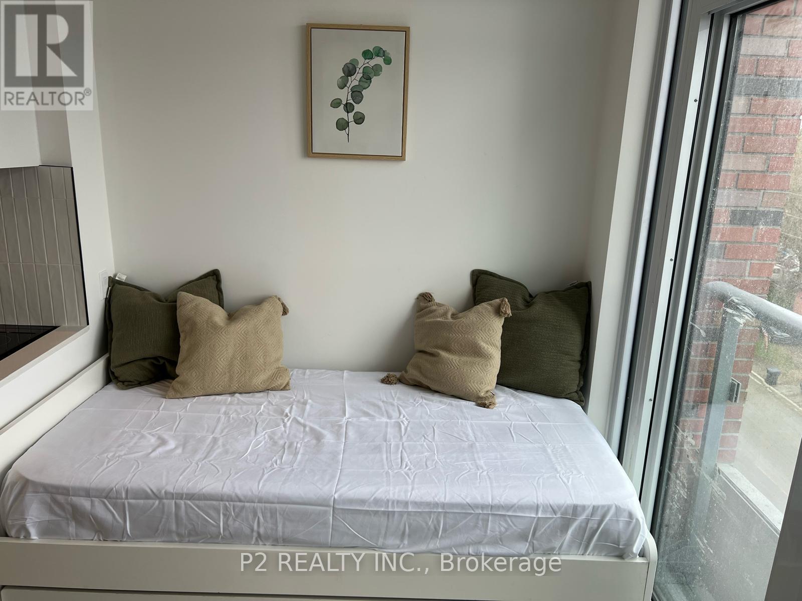 A bedroom with a bed, pillows, and a picture on the wall.