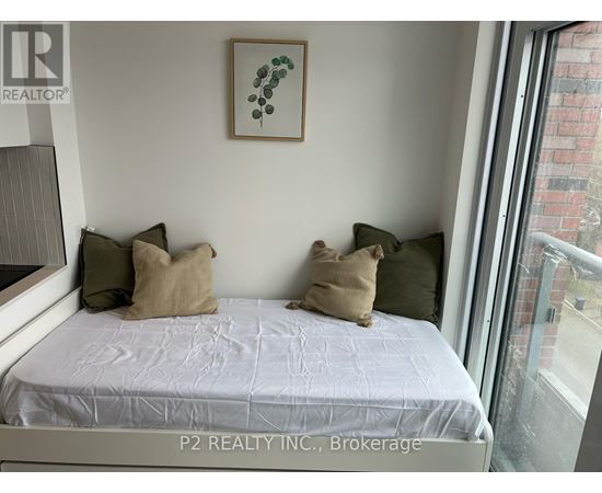 A bedroom with a bed, pillows, and a picture on the wall.