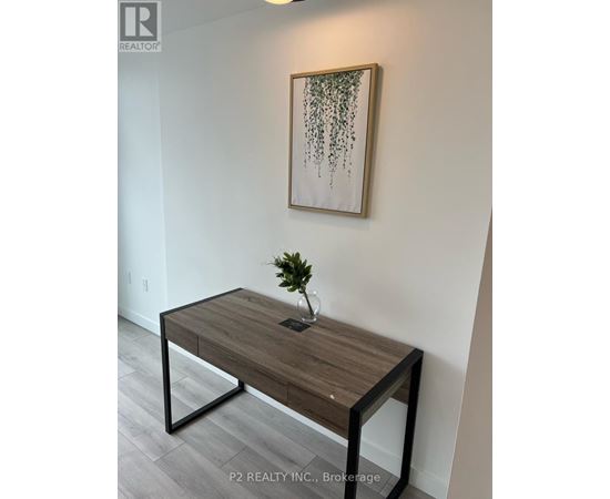 A table with a plant on it and a picture on the wall.