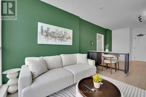 A living room with a white couch and a coffee table with a vase of flowers on it.