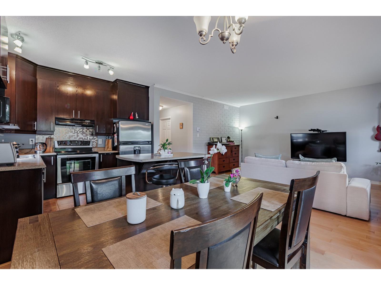 A modern kitchen with dark wood cabinets and a dining table set for two.