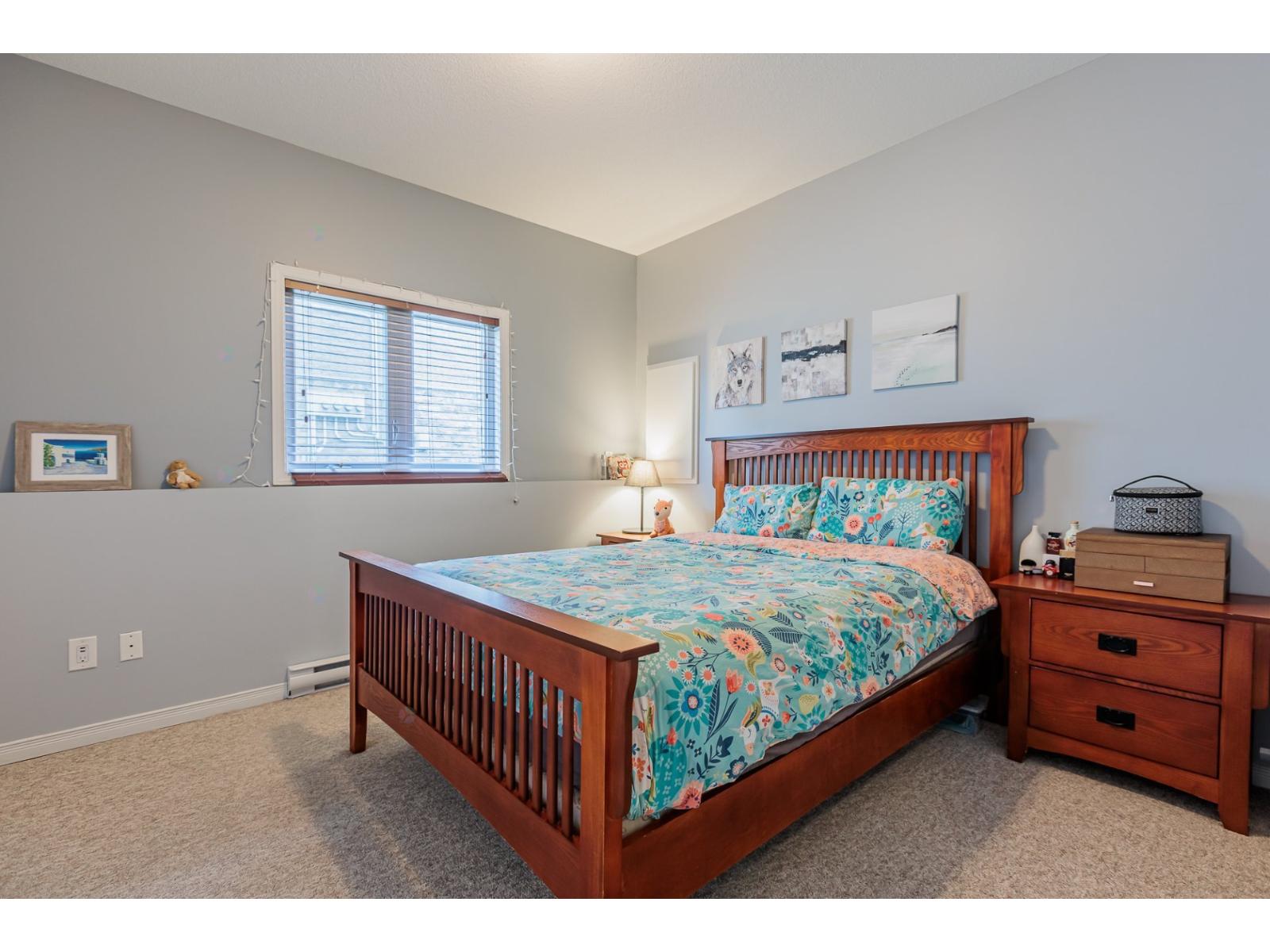 A bedroom with a bed, nightstand, and window.