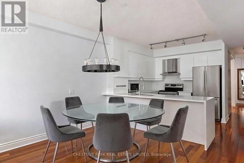 A modern kitchen with a glass table and grey chairs.